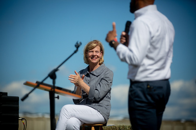 Tammy Baldwin listens to another candidate give a speech at political talk. 