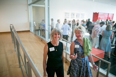 Two gals are walking and talking at an art opening at the Madison Contemporary of Museum of Art. 