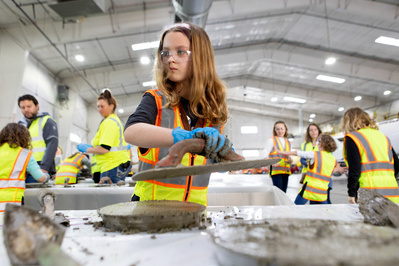 A kid a working intently on a cement  project.
