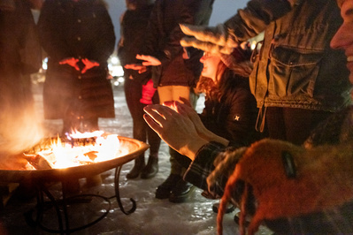 People are warming their hands over a fire pit on Lake Mendota.