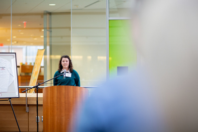 A gal gives a talk at a podium at the Morgridge Institute of Research at the University of Wisconsin.