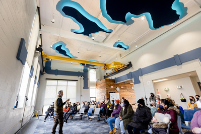 Someone is talking to a group at the Madison Sewer District. The photo is taken so you can see the ceiling and it's cool cause there are outlines of lakes on the ceiling that are lit up! 