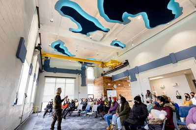 Someone is talking to a group at the Madison Sewer District. The photo is taken so you can see the ceiling and it's cool cause there are outlines of lakes on the ceiling that are lit up! 