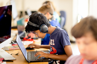 A kid is intensely looking at his computer at summer camp at the UW Wisconsin. 
