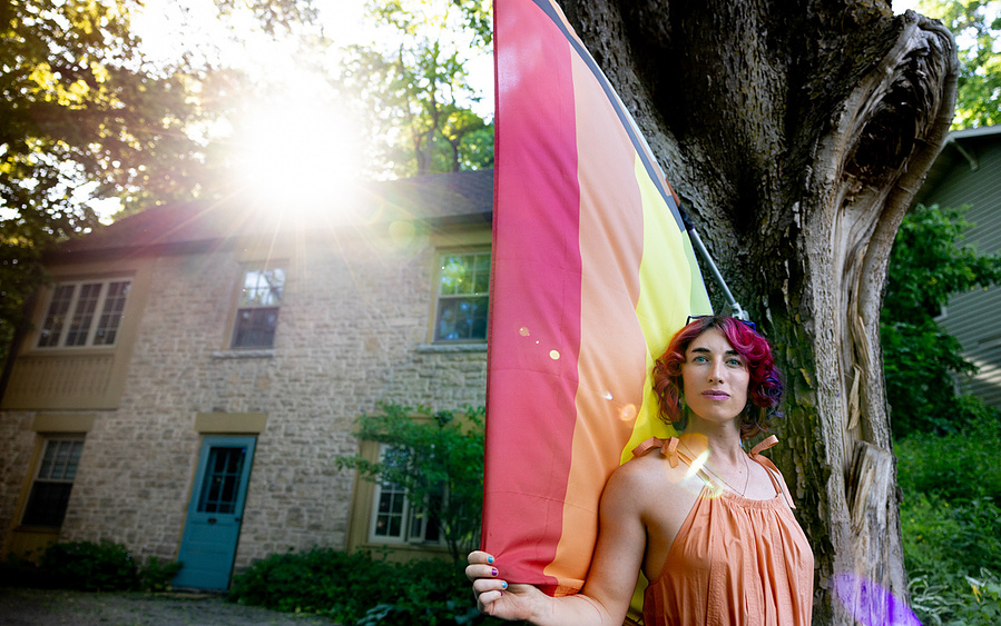 This nice transgender gal is posing in a front a pride flag in front of her house. 