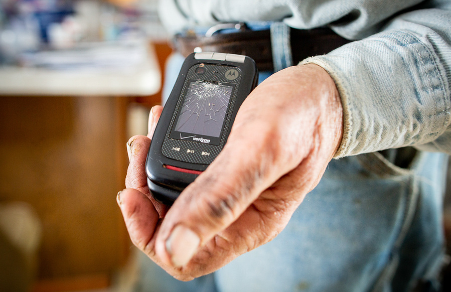 A farmer holds an old flip phone. I love an old flip phone--it's so cool! 
