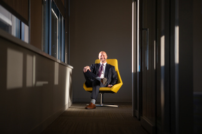 A  businessman wearing a suit sits in a  chair.