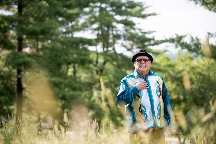 A Native American man stands in a field. 