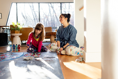 mother daughter play on the floor together in their sunlit room. shiming bright and colorful and happy portrait