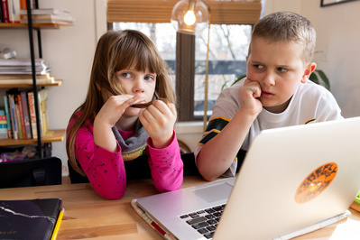 family portrait of a brother and sister working on the computer at their kitchen table