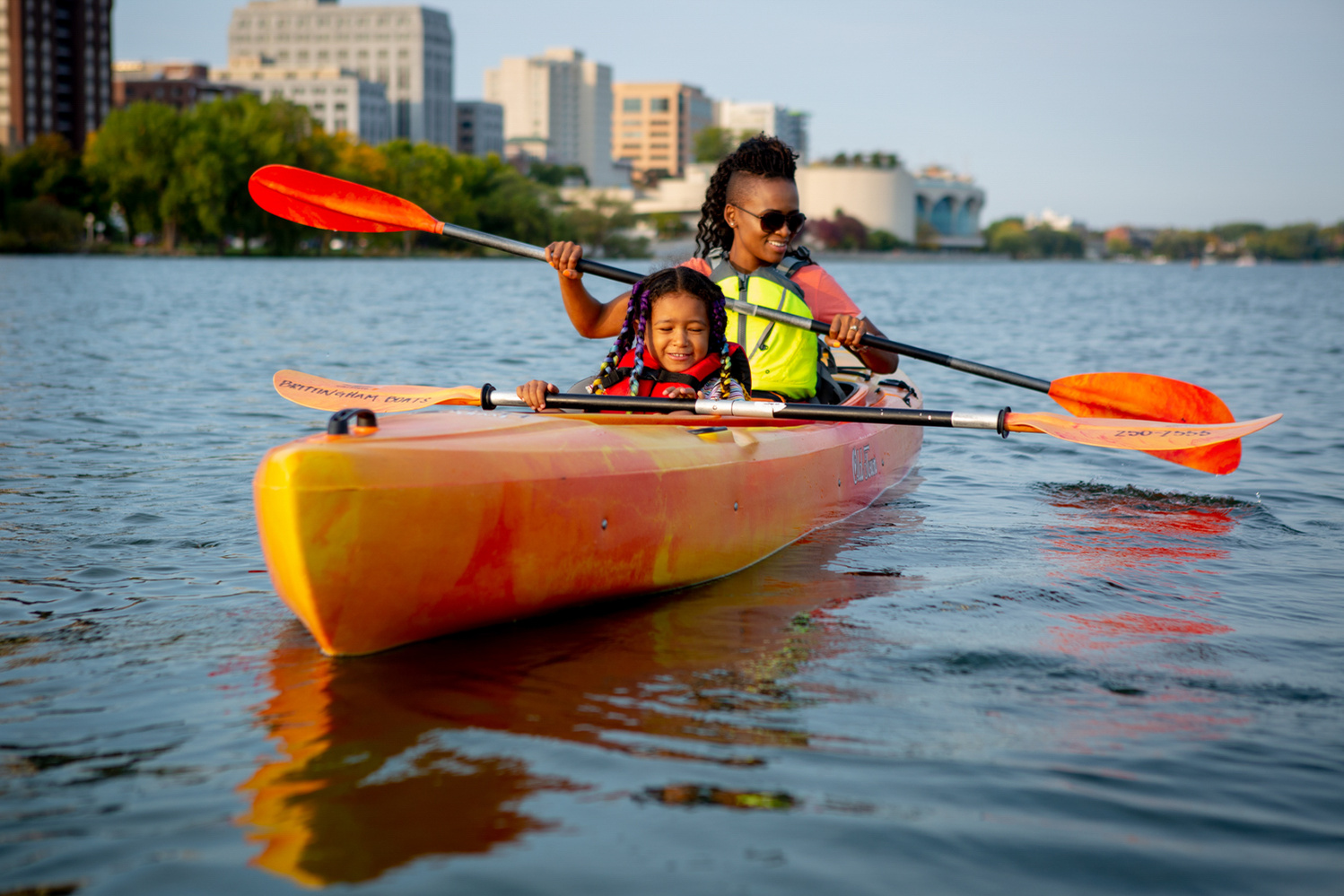 Lifestyle photography of mother and daughter kayaking on Lake Monona in Madison, WI.  The family paddles their kayak near the Monona Terrace.