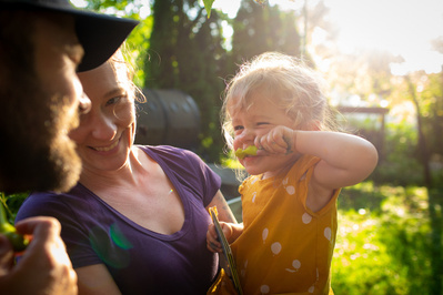 a beautiful glowing sun shines behind this family photo. mother father and child candidly captured in family documentary photo