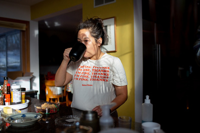 A portrait of a mom drinking coffee in the morning light of her kitchen.