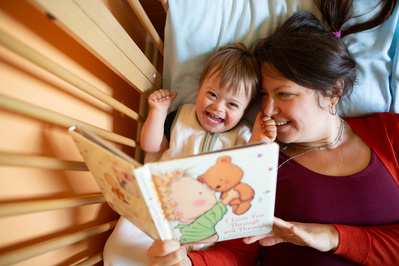 A glowing smile from a toddler being read to by his mom in this family photo.