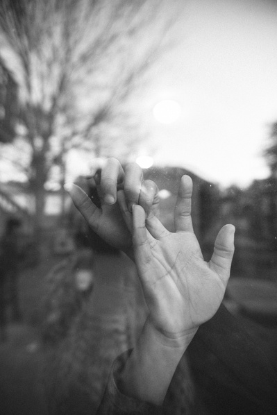 Artistic family photo in black in white, a hand reaches to the window,