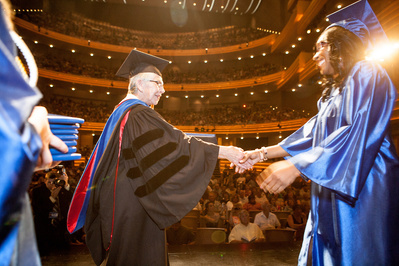 A young graduate receives a diploma from Madison College graduation in Madison Wi. 