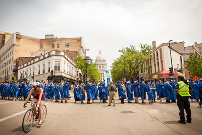 A group of Madison College students wearing graduation gowns walk down state street to their ceremony at the Overture Center. 