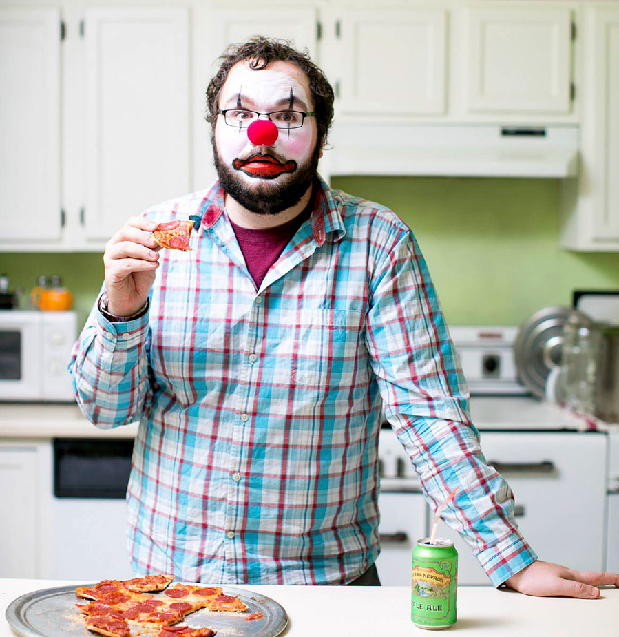 A clown eats pizza. Just an everyday event. 