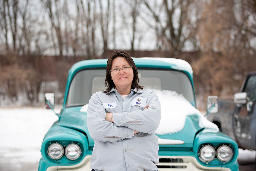A women from Dutches Auto Body in Madison, Wi poses by an old car. 