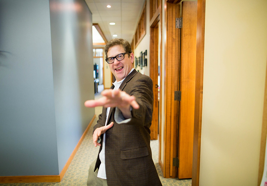 A businessman guy poses for the camera in a hallway.