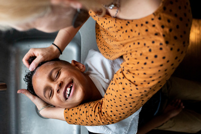 a mother washes her sons hair as he smiles in this kids photo