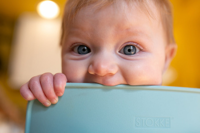 A portrait of a toddler teething on their couch.