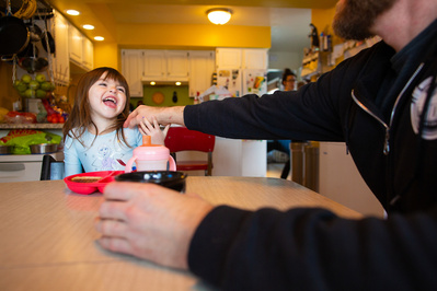 a daughter laughs and smiles at her father in this candid portrait