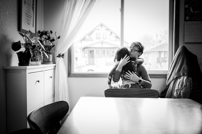 an intimate family portrait as a father and daughter share a hug. the photo is black and white
