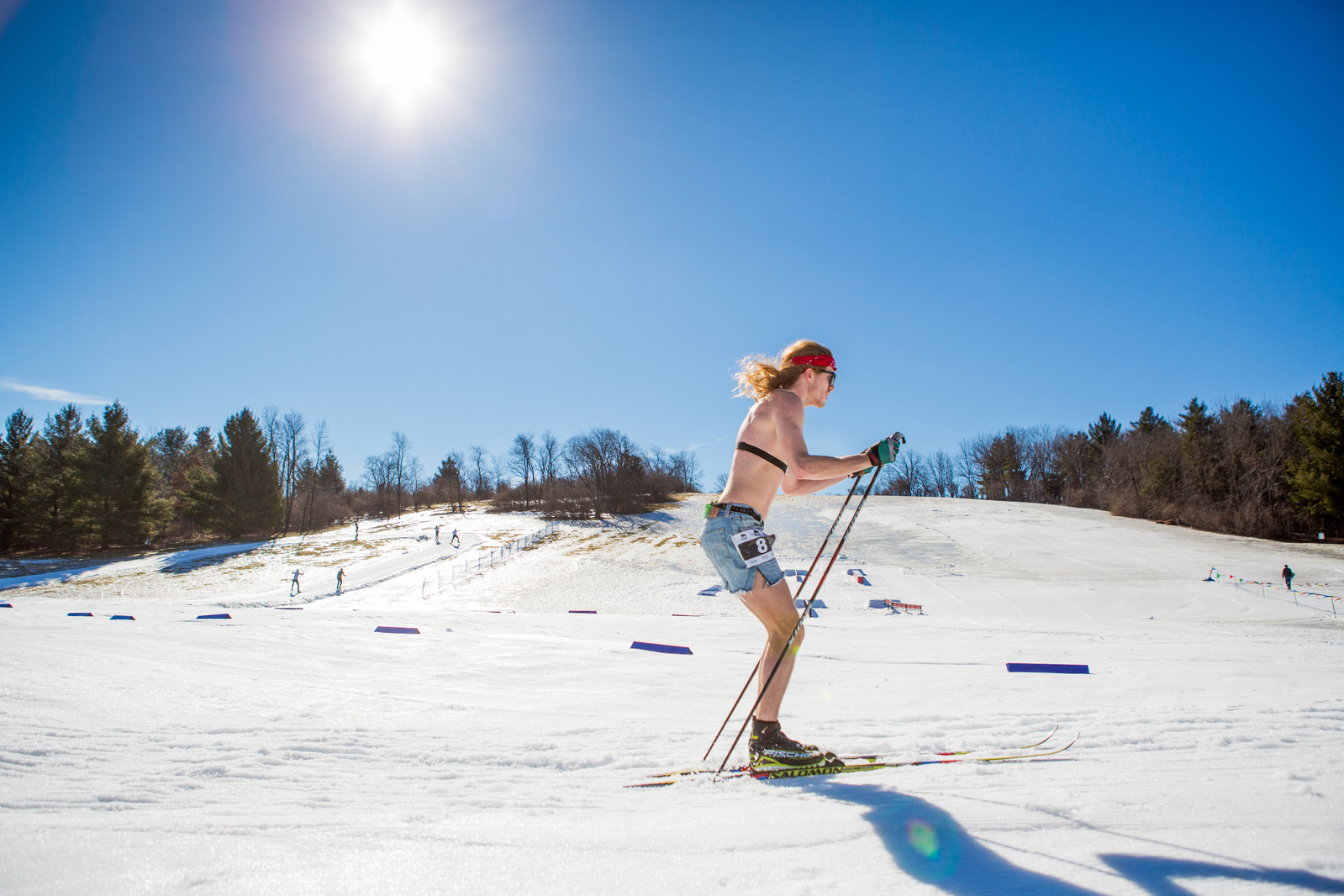 A cross country skier enjoys a warm day during the Winter season as sunshines on a snow covered field in this commercial photograph.