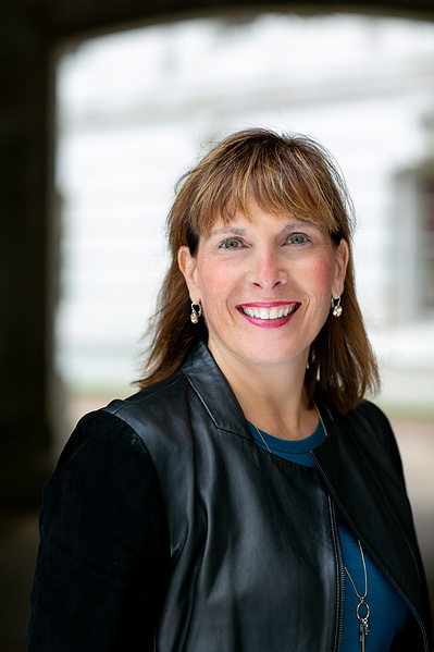 A women is smiling and wearing a coat. 