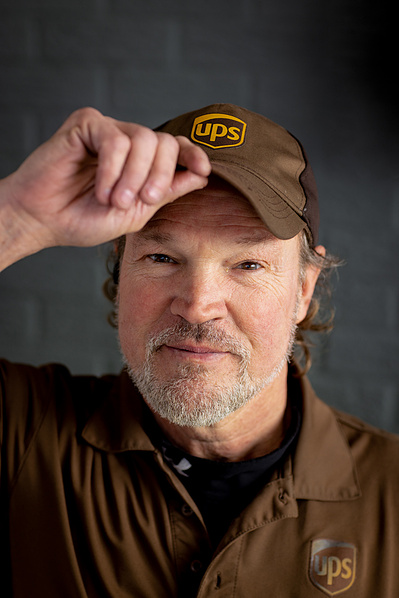 A UPS driver holds his hat. 