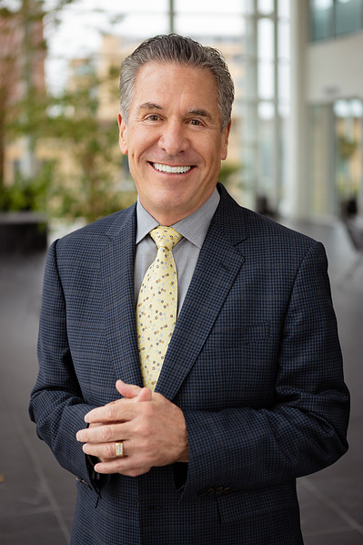 A man wearing a suit smiles at the camera.