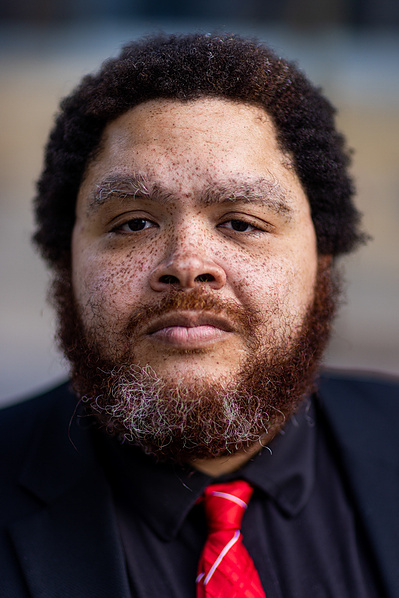 A man with a beard and red tie and so many cute cute freckles gets his photo taken. 
