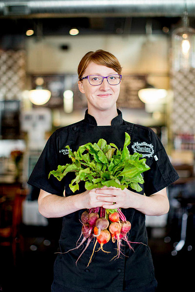A women chef holds a bunch of radishes. 