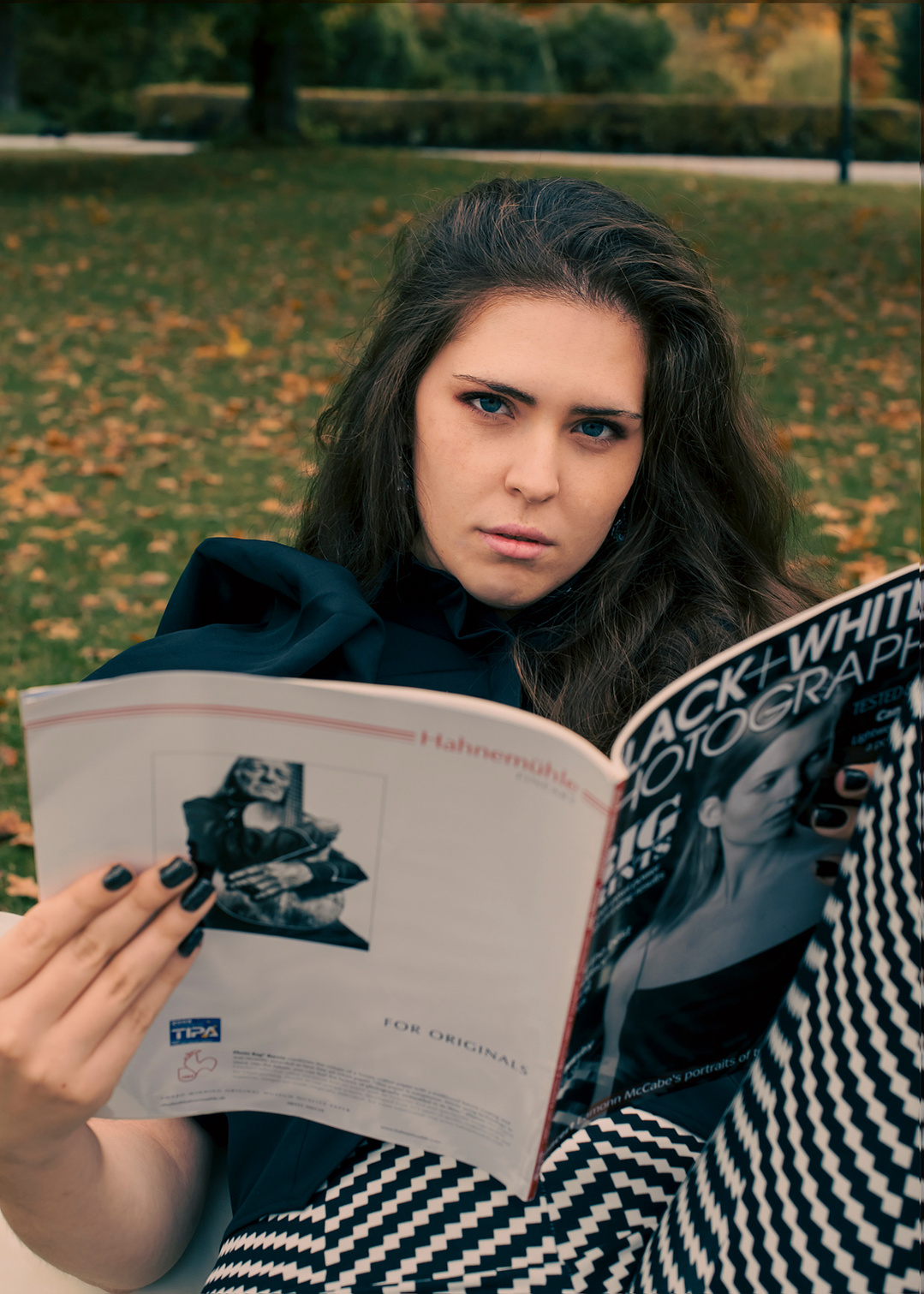 Modernes Mode-Fotoshooting: Mädchen in Schwarz-Weiß-Bekleidung liest entspannt ein Magazin – stilvoll und urban. Niederösterreich, Tulln, Krems an der Donau