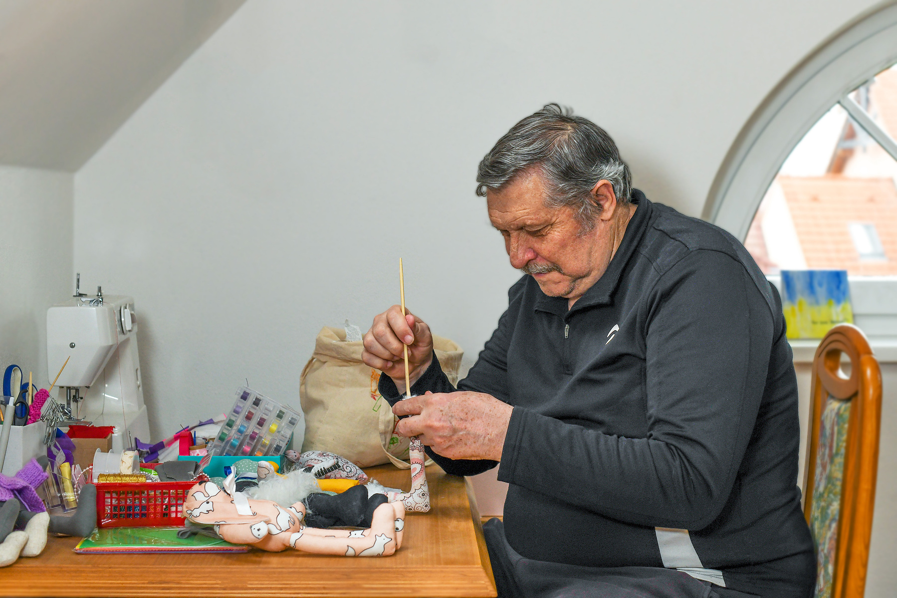 Opa konzentriert bei der Arbeit an einer Stickerei – liebevolles Portrait handwerklicher Tradition. Niederösterreich, Tulln, Krems an der Donau