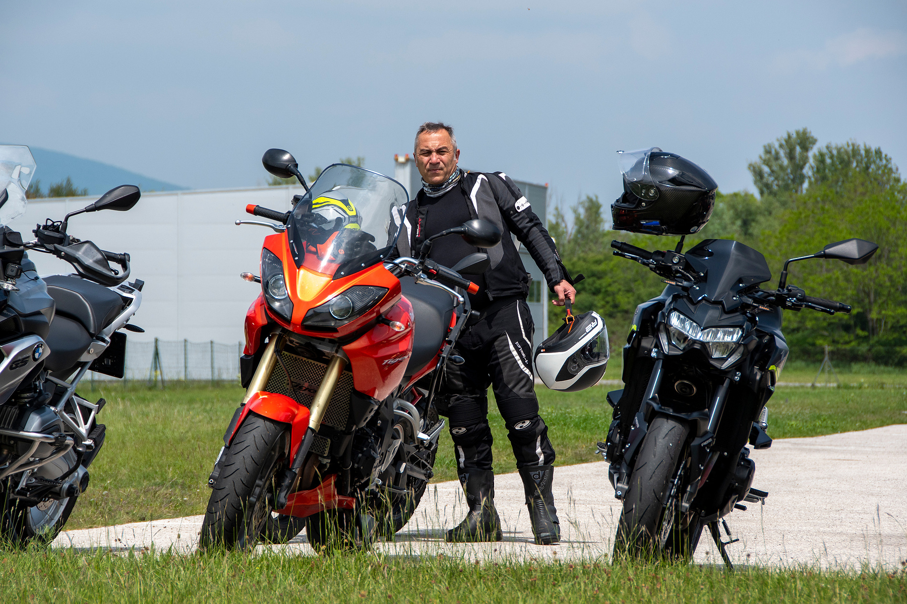 Motorradfahrer steht zwischen zwei BMW-Motorrädern – rot und schwarz – kraftvolles Bild von Stil und Technik. Niederösterreich, Tulln, Krems an der Donau