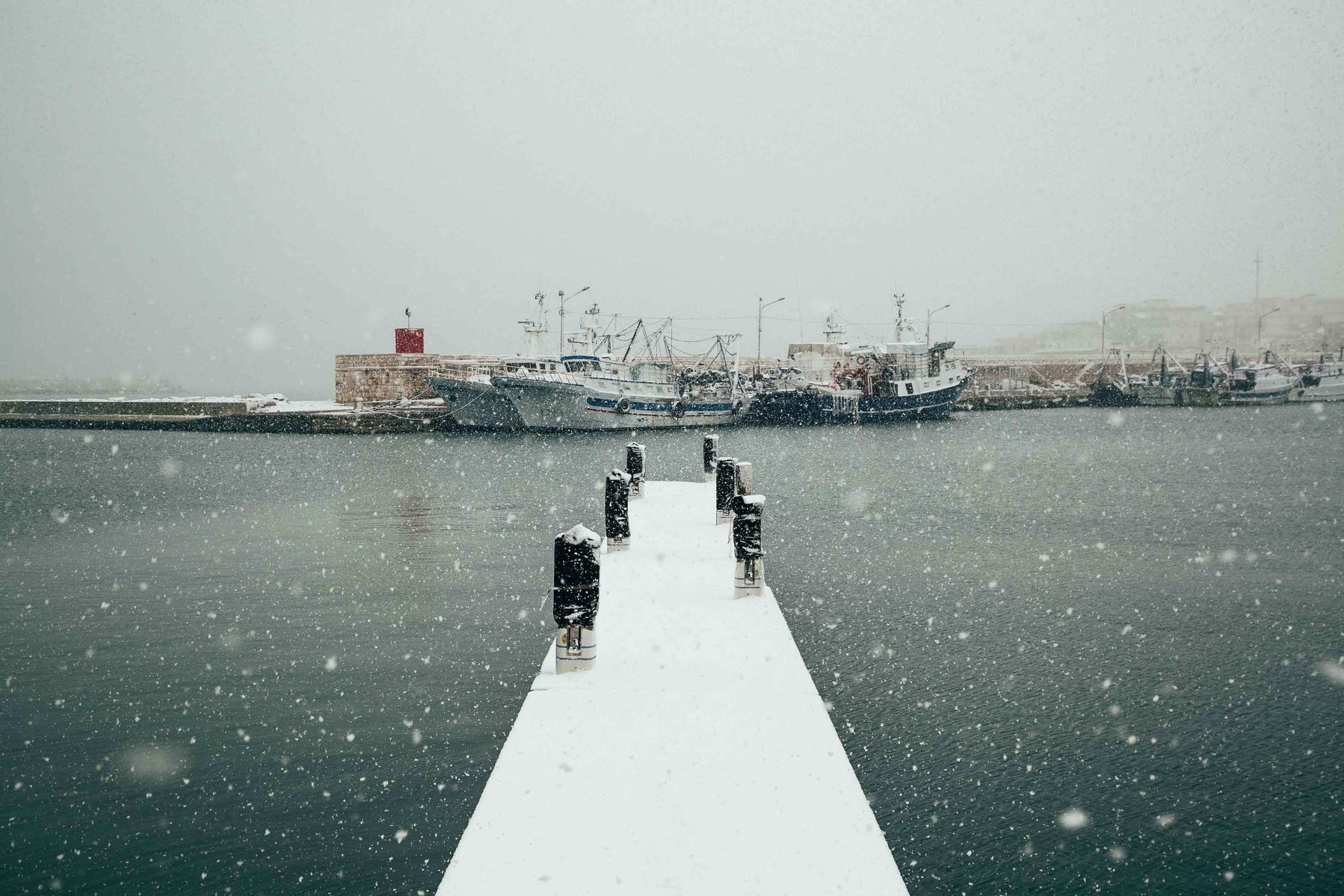 bridge in Bisceglie's harbor covered by snow
