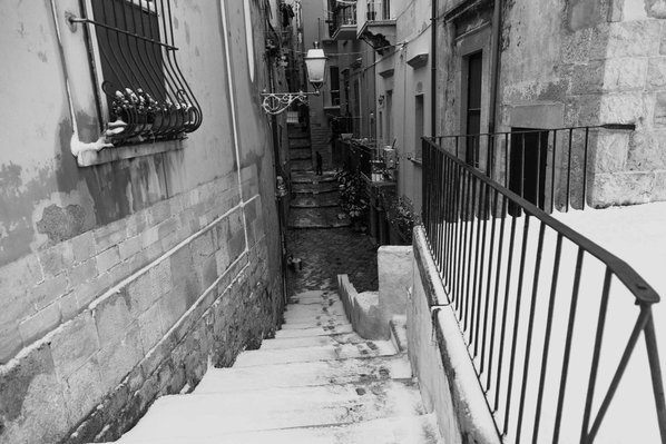 Black and white photo of a man walking in Bisceglie during a snowfall