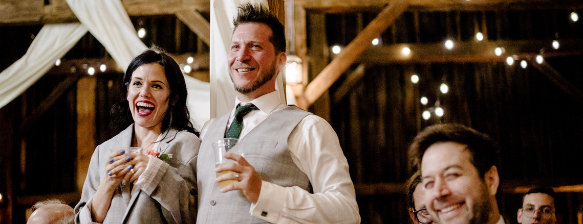 Bride and Groom relaxing and smiling at their wedding with drink in hand. 