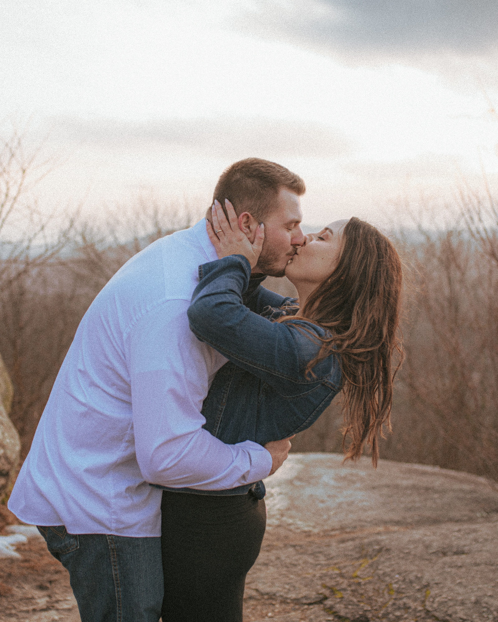 A couple kisses at Jump Off Rock in Hendersonville, NC during an engagement photography session
