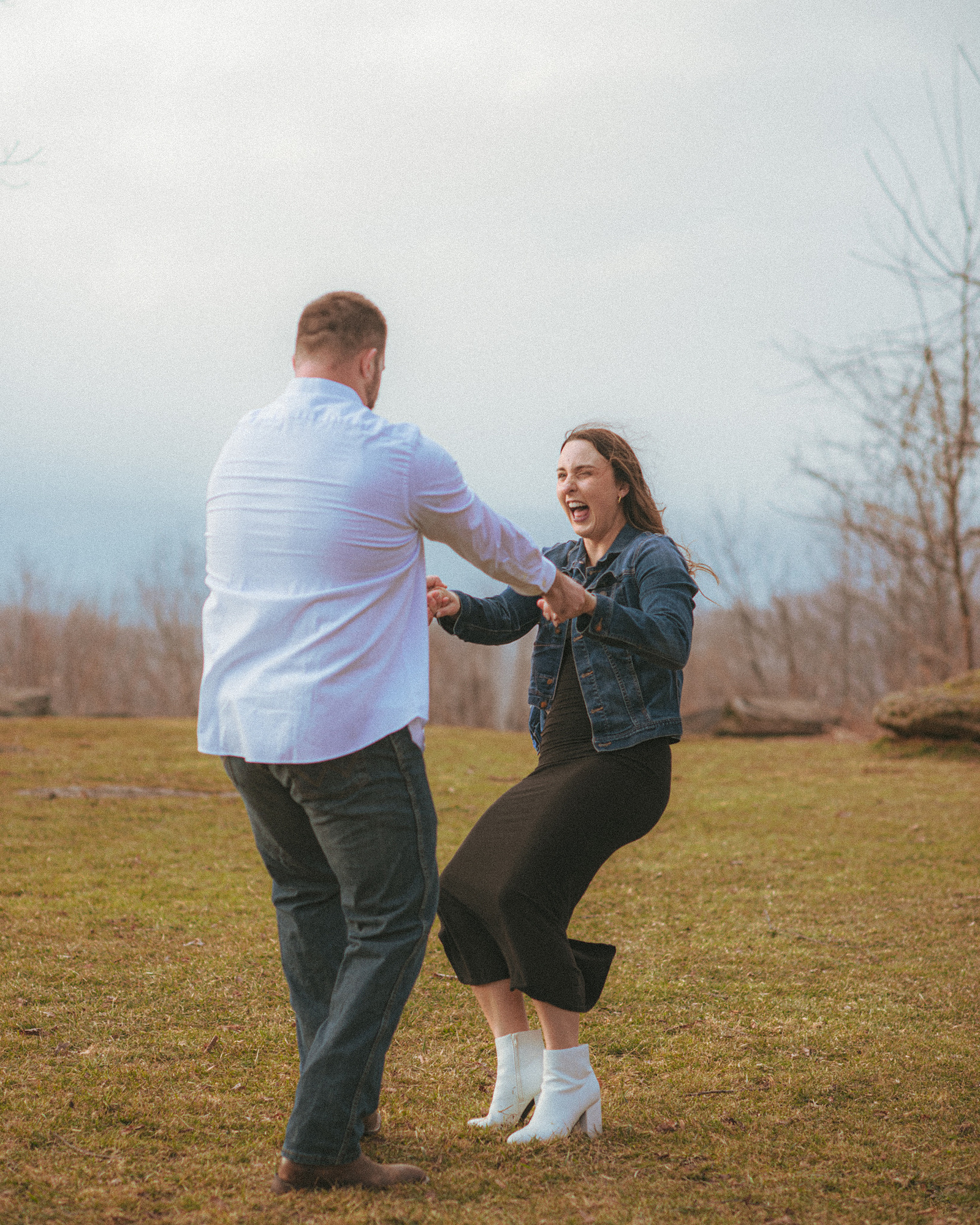 A couple laughing near sunset at Jump Off Rock in Hendersonville, NC during an engagement photography session