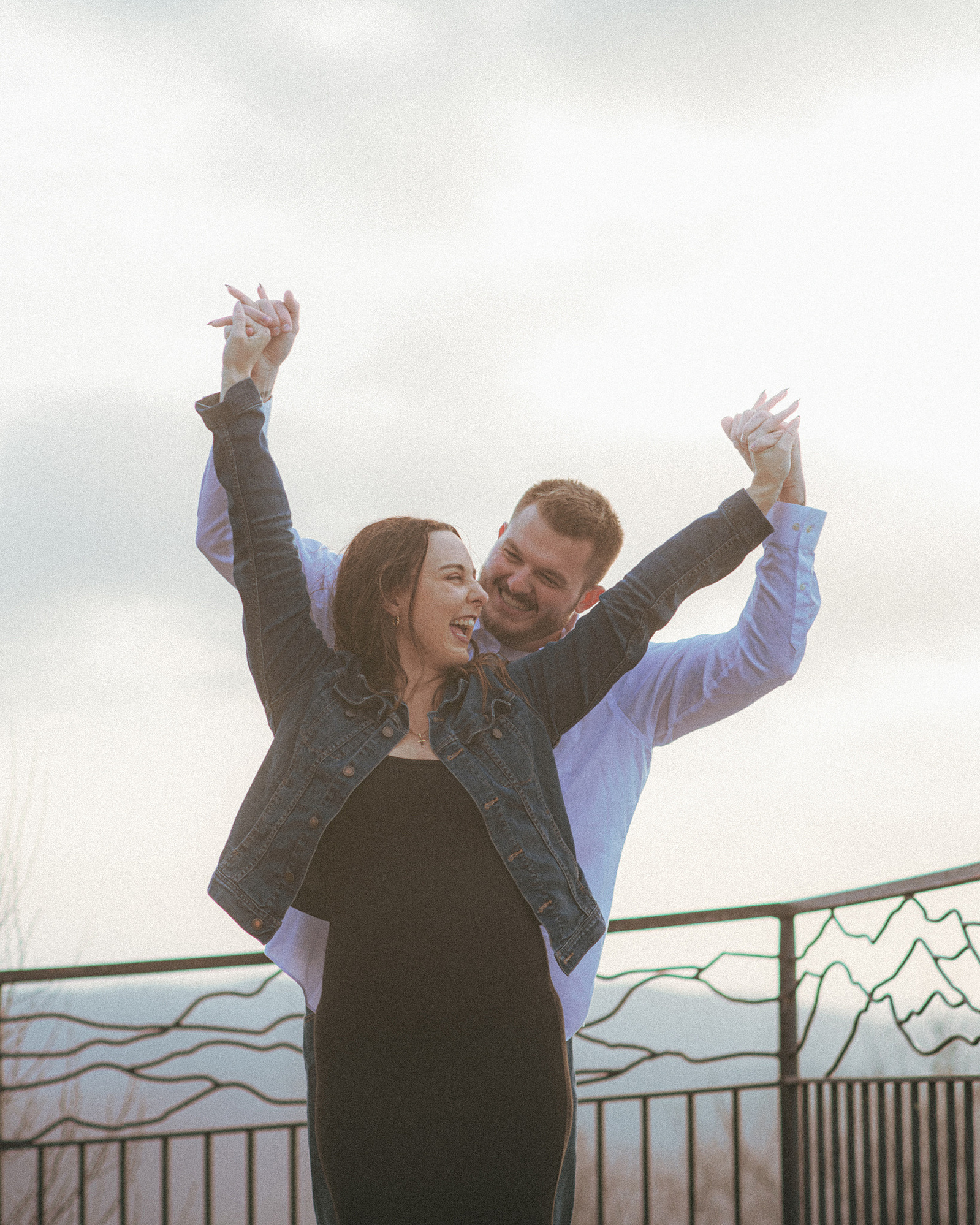 A couple laughing near sunset at Jump Off Rock in Hendersonville, NC during an engagement photography session