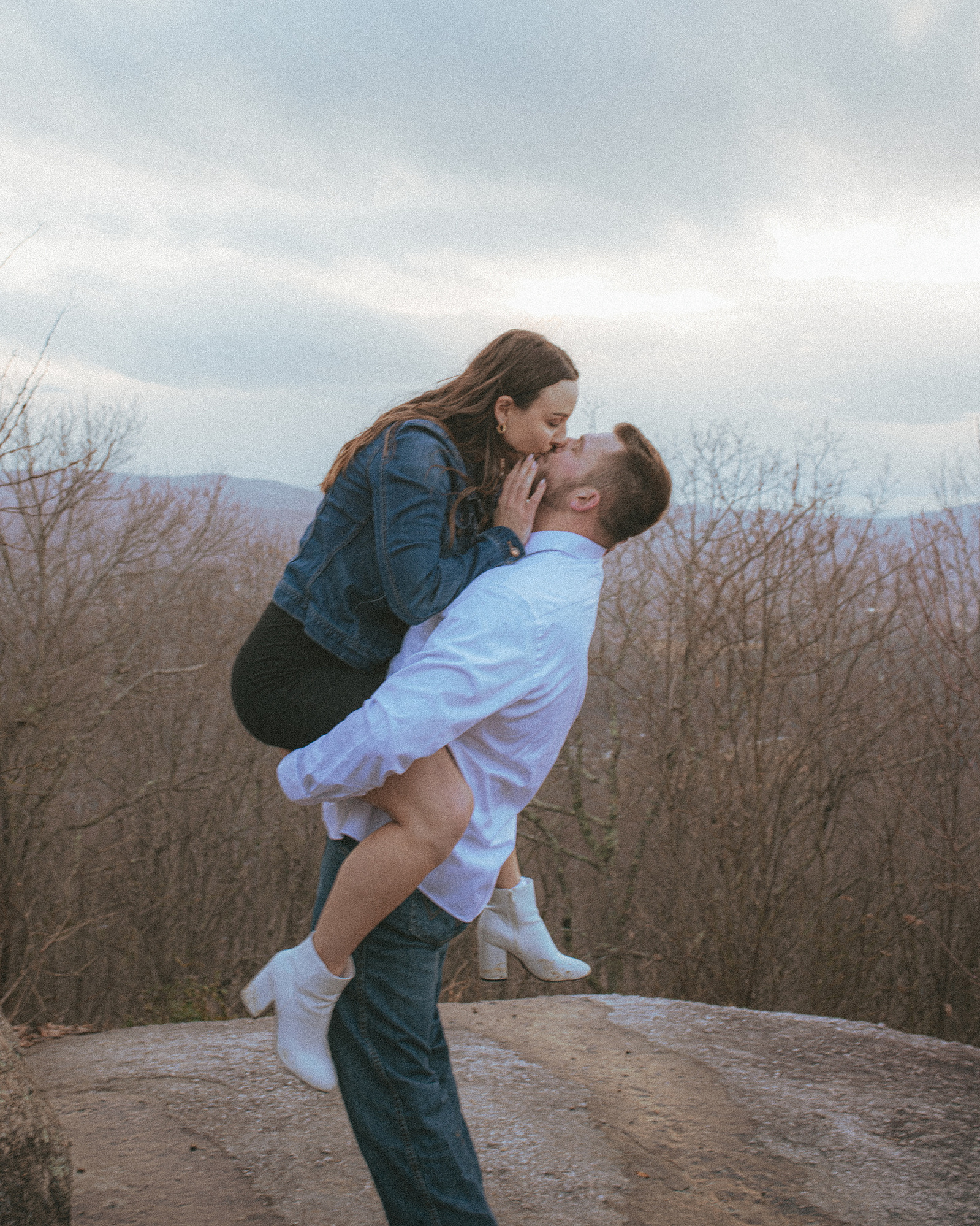 A couple kisses at Jump Off Rock in Hendersonville, NC during an engagement photography session