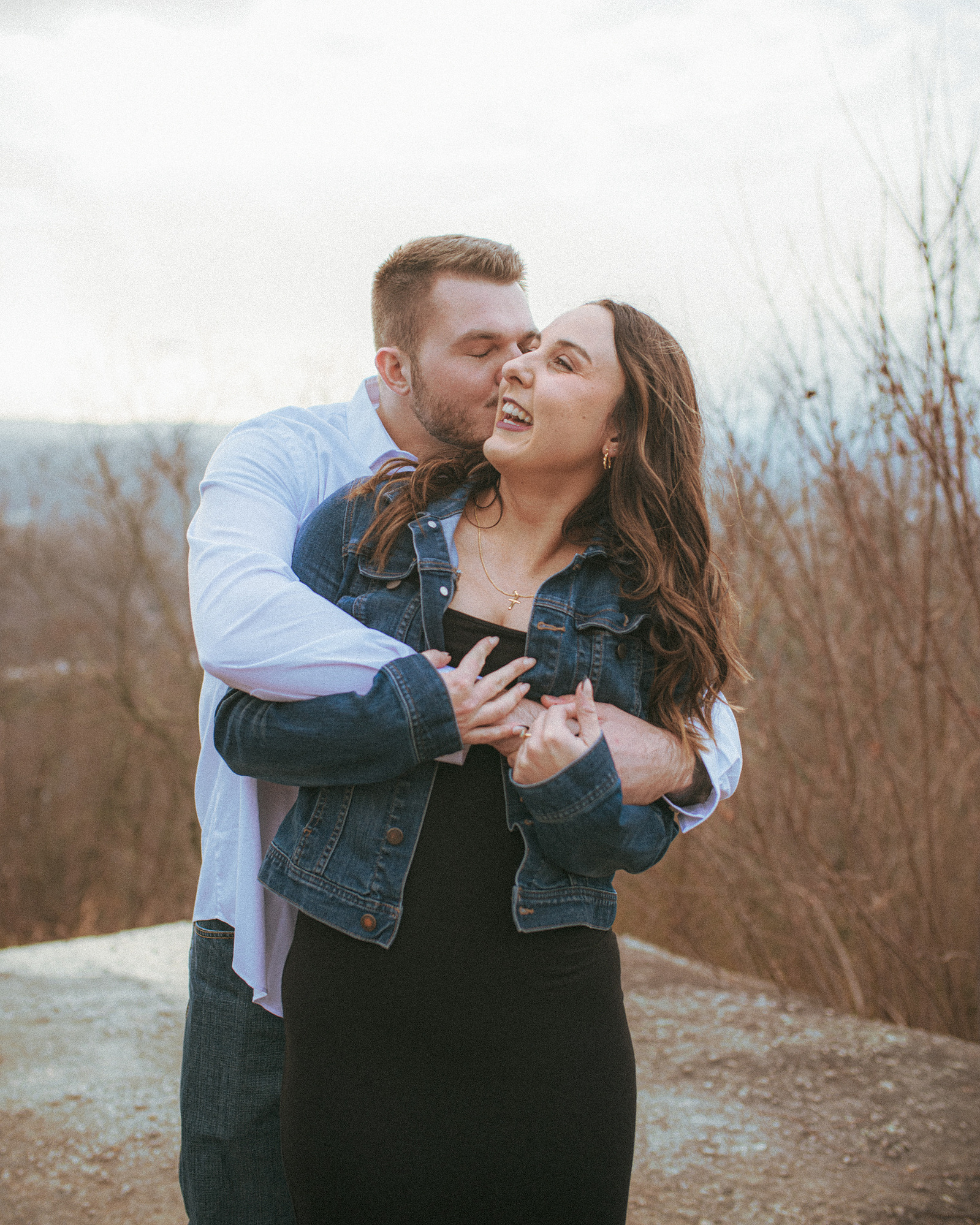 A couple laughing at sunset on Jump Off Rock in Hendersonville, NC during an engagement photography session