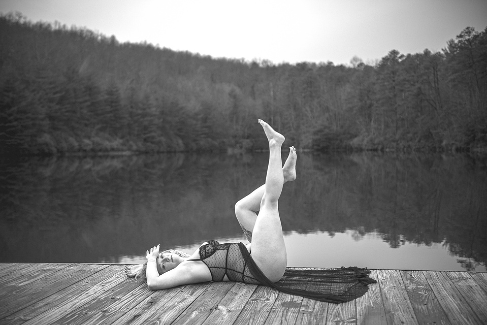 Woman posing on the dock of a lake during an outdoor boudoir photography session at a lake in DuPont Forest near Asheville, NC