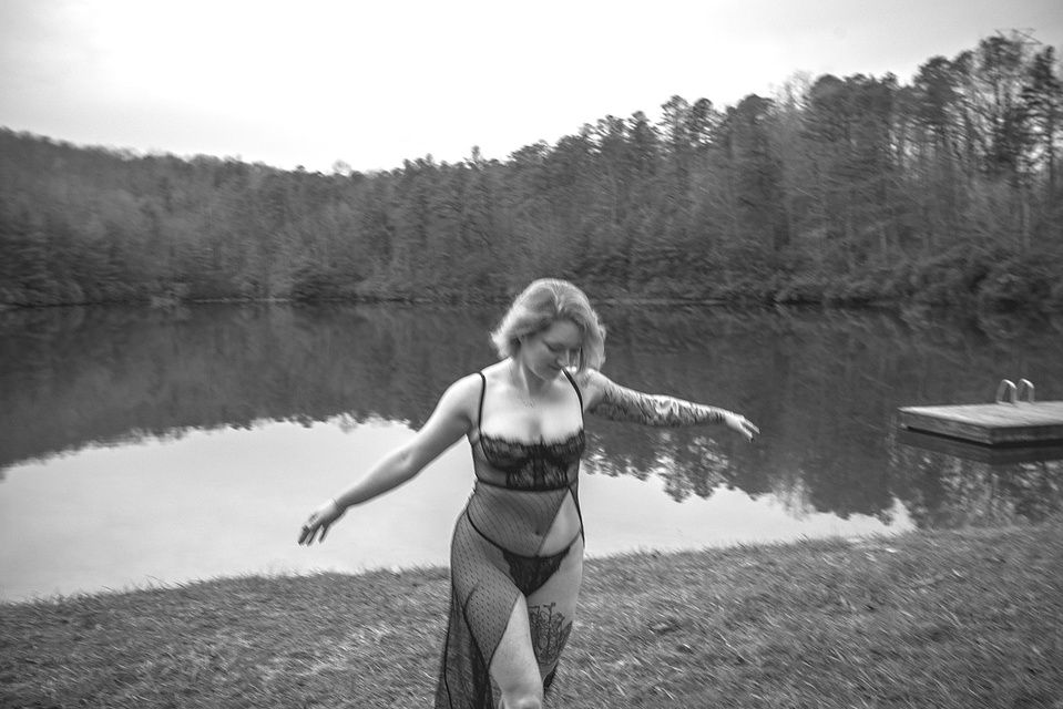 Woman walking by a lake during an outdoor boudoir photography session at a lake in DuPont Forest near Asheville, NC