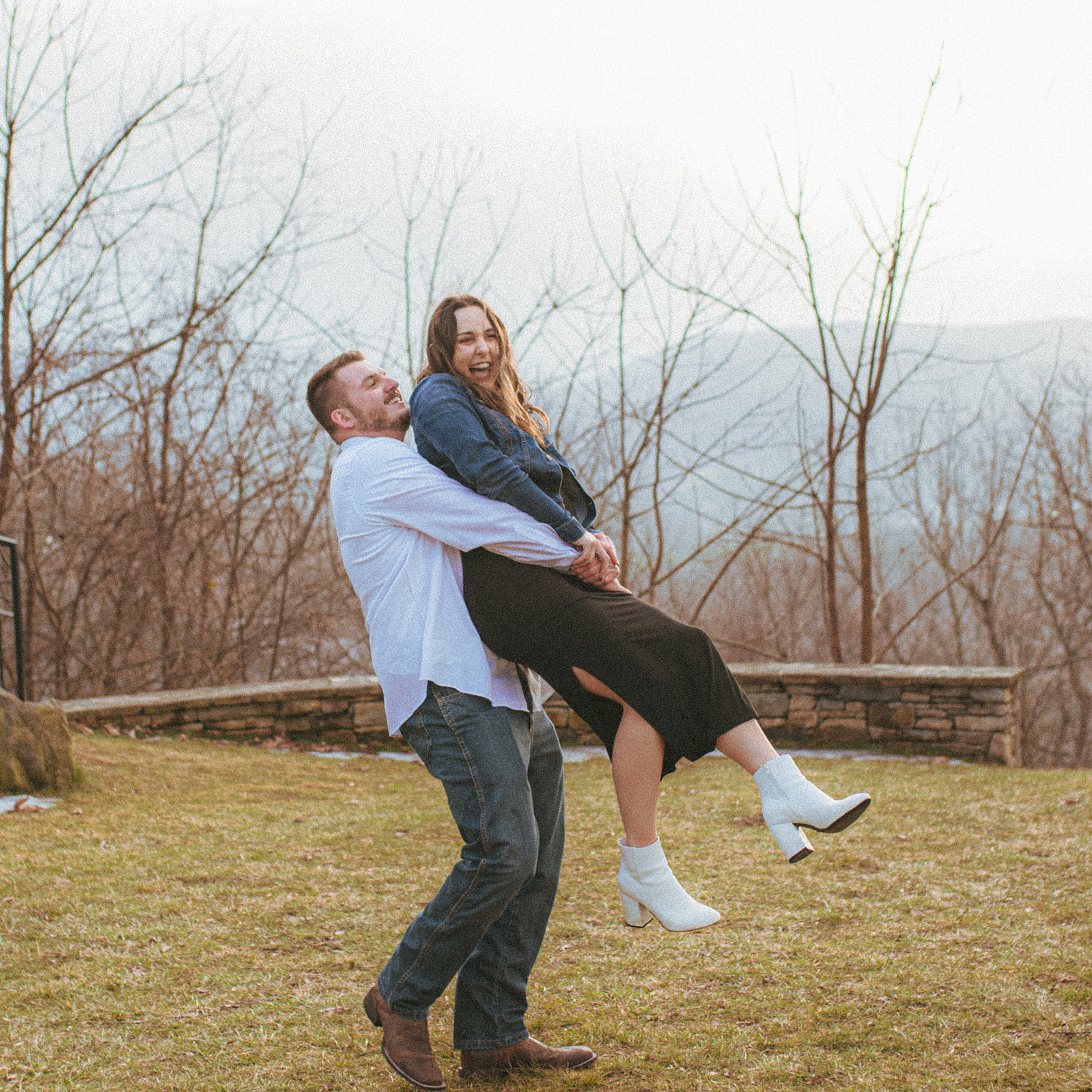 A couple laughing near sunset at Jump Off Rock in Hendersonville, NC during an engagement photography session