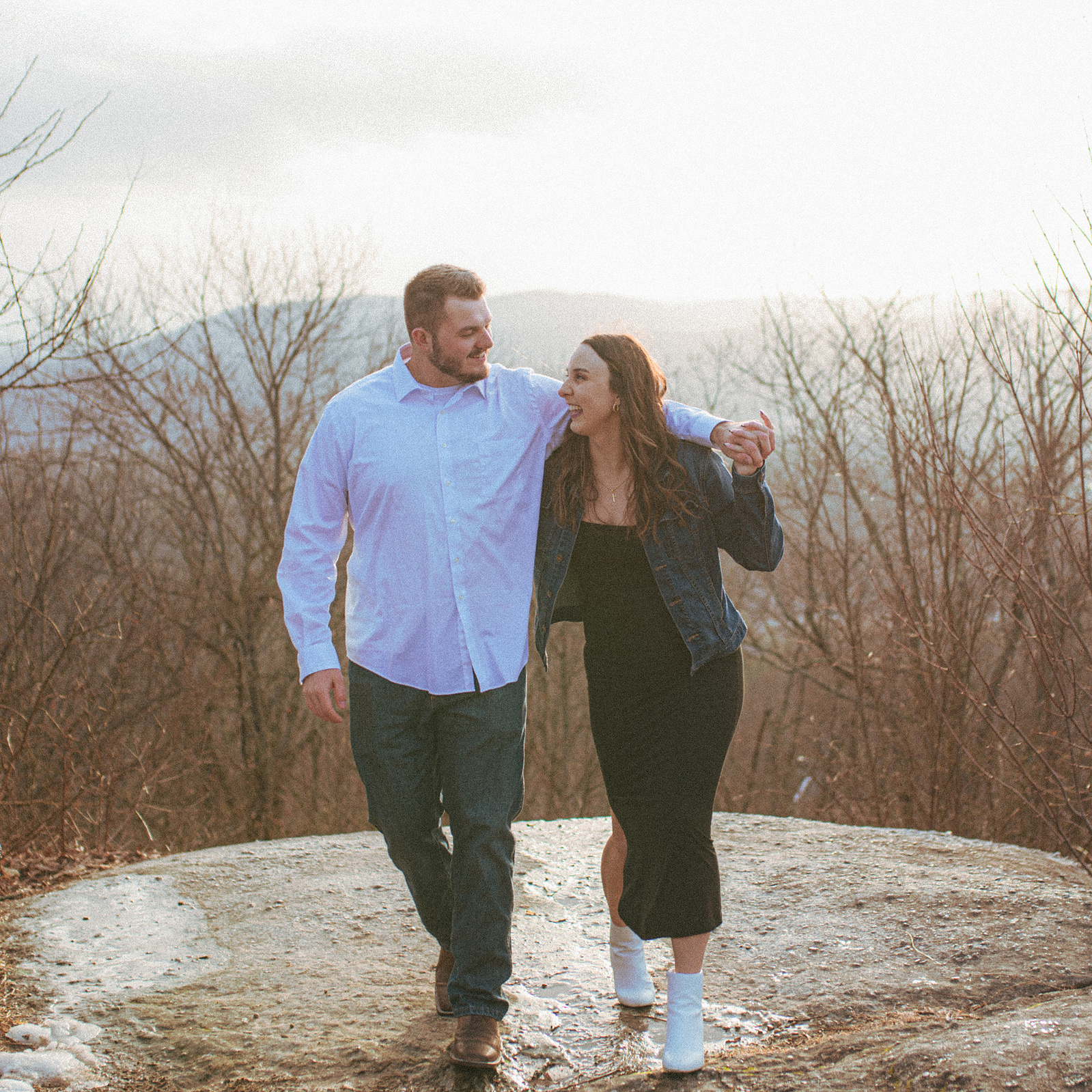A couple laughing near sunset at Jump Off Rock in Hendersonville, NC during an engagement photography session