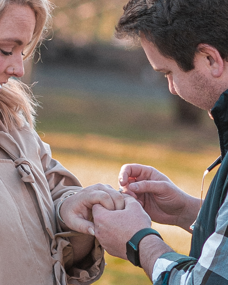 A man places a ring on his fiance after proposing on the High Lawn at the Biltmore Estate in Asheville, NC